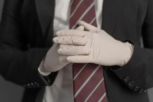 Businesswoman putting on disposable gloves. Selective focus on female hand in foreground. Preventive measures concept. Close up shot.