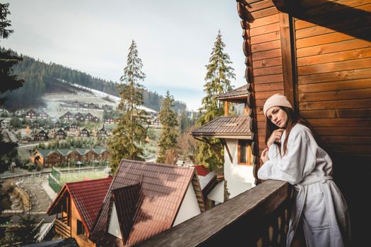 The girl is standing on a terraced house in a mountainous area. In good winter weather.