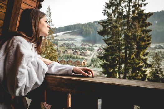 The girl is standing on a terraced house in a mountainous area. In good winter weather.