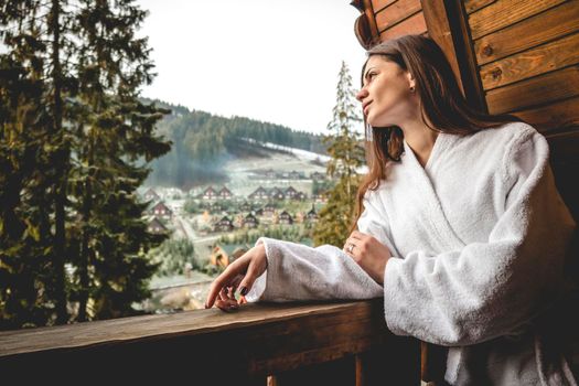 The girl is standing on a terraced house in a mountainous area. In good winter weather.