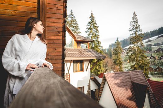 The girl is standing on a terraced house in a mountainous area. In good winter weather.