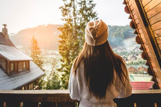 The girl is standing on a terraced house in a mountainous area. In good winter weather.