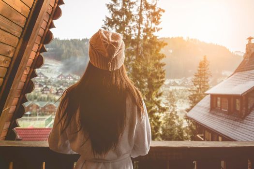 The girl is standing on a terraced house in a mountainous area. In good winter weather.