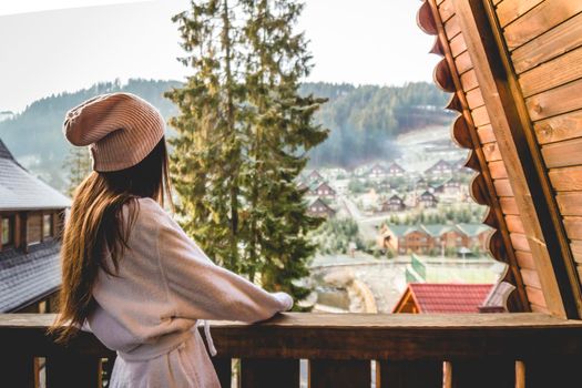 The girl is standing on a terraced house in a mountainous area. In good winter weather.