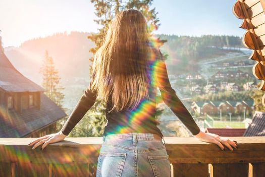 The girl is standing on a terraced house in a mountainous area. In good winter weather.