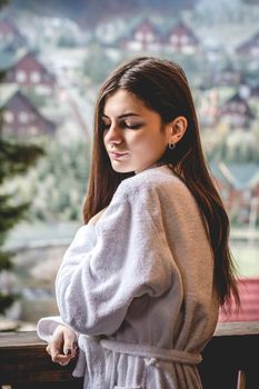 The girl is standing on a terraced house in a mountainous area. In good winter weather.