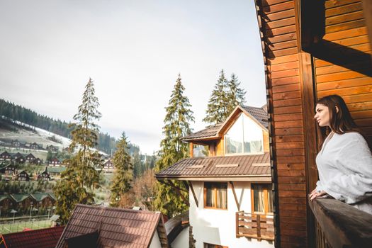 The girl is standing on a terraced house in a mountainous area. In good winter weather.