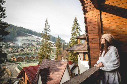 The girl is standing on a terraced house in a mountainous area. In good winter weather.
