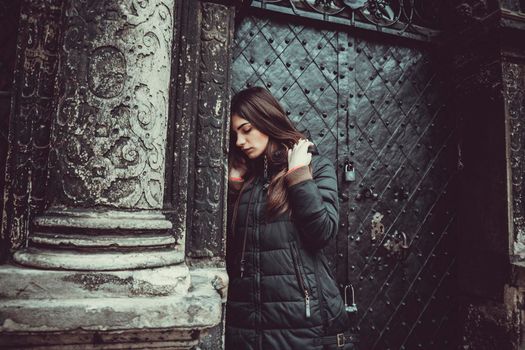 The young girl stands on the background of the old gothic wall.
