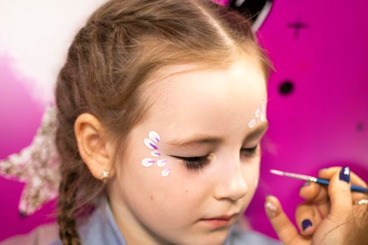 childrens makeup face paint drawings Girls face painting. Little girl having face painted on birthday party. closed eyes. High quality photo