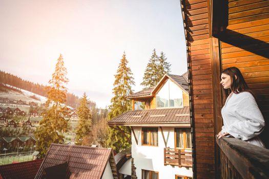 The girl is standing on a terraced house in a mountainous area. In good winter weather.