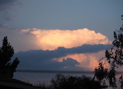 cloudscape at sunset on the lake with black silhouettes of trees