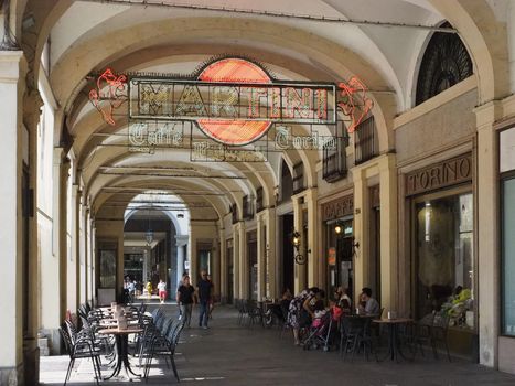 People walking under Piazza San Carlo square colonnade in Turin, Italy