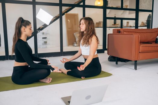 Two young women meditating in lotus pose. Yoga