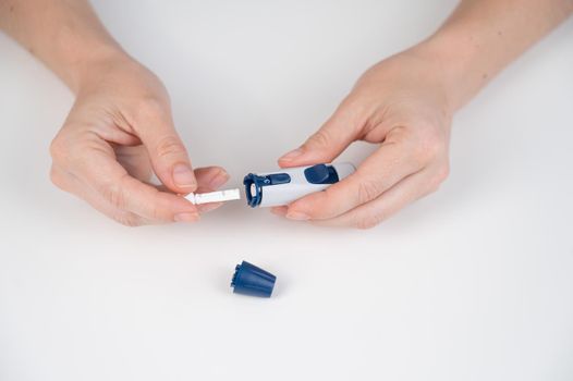 Caucasian woman inserts a needle into a lancet pen