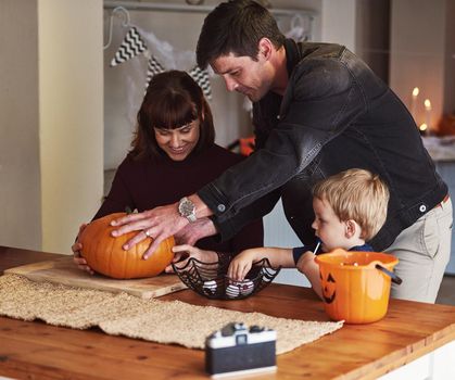 Were getting into the spirit of halloween. an adorable young family carving out pumpkins and celebrating halloween together at home