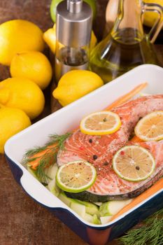 Steak of red fish and sliced lemons on white.