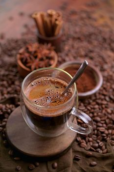 Tasty steaming espresso in cup with coffee beans. View from above. Dark background.