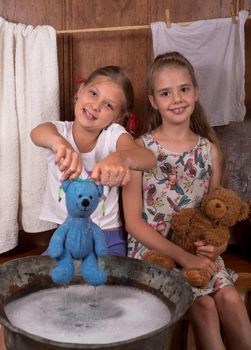 two girlfriends. Cute happy girls bathe teddy bears, blow bubbles.