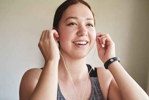 Music ready, lets go. an attractive young woman standing alone and listening to music through earphones before her workout at home