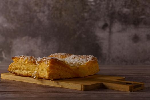 apple tartlet topped with syrup and shredded coconut, on a wooden board