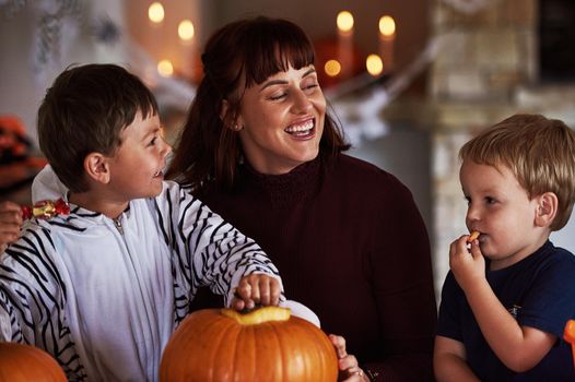 Mommys little monsters. two adorable little boys carving out pumpkins and celebrating halloween with their mother at home