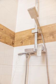 Close-up of plumbing equipment. New, clean, chrome, shower and a small pendant on a white wall, copy and paste your design. the concept of hygiene, body wash, body care products