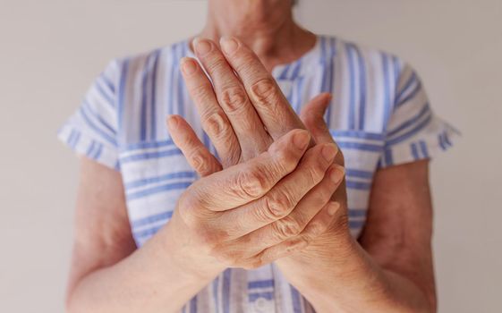 Close-up of woman's old hands. Rheumatoid arthritis. Osteoarthritis of an elderly man and an elderly woman suffering from pain at home. Massage of the hands and fingers.