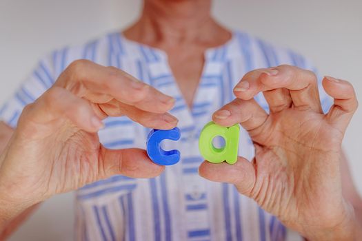 Close-up, woman holds the letters C A in her hands, calcium, concept of prevention and treatment of diseases of the joints, bones, arthritis, arthrosis in the elderly. Bioshowers, pills, body support