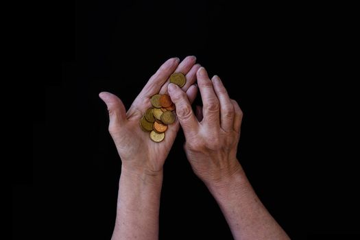 top view, flat lay. Close-up, the hands of an old, wrinkled white woman counting coins, cents. The concept of poverty. Small unemployment benefits, expensive drugs, higher prices, higher food prices