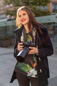 Portrait of professional female photographer on the street photographing on a camera. Photo shoot photosession in the city