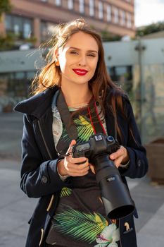 Attractive tourist woman photographer with camera, outdoor in city street. Gorgeous happy caucasian female in casual hipster clothes