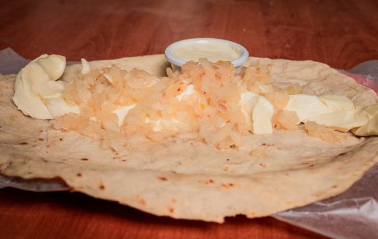 Close up of Nicaraguan Quesillo served on wooden table. Top view of Nicaraguan Quesillo served on wooden table. Traditional Nicaraguan Quesillo served on wooden table