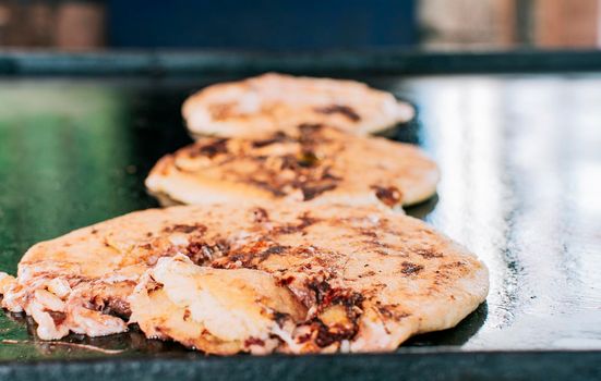 Traditional Nicaraguan pupusas with melted grilled cheese, Traditional cheese pupusas on the grill, Close up of traditional handmade pupusas on the grill.