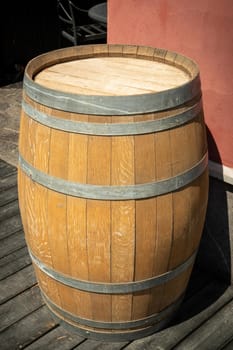 An oak barrel stands on the outdoor near the wall.