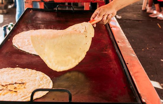 Traditional handmade Nicaraguan tortillas, Traditional handmade corn tortillas on the grill. Hands preparing traditional tortillas on grill, Close up of hands flipping tortillas on grill