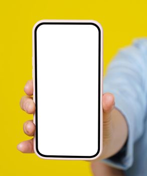 Woman hand holding smartphone with white screen in pink case isolated on yellow background. Modern phone with touch screen in woman hand. Close up. Mock up mobile app advertising.