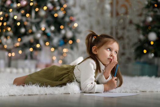 Cute little girl with ponytails is writing a letter to santa claus.