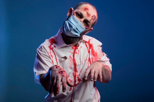 Brain eating zombie posing on camera, looking frightening and creepy with bloody scars and wounds. Undead halloween corpse with dangerous look and wounded face during covid 19 pandemic.