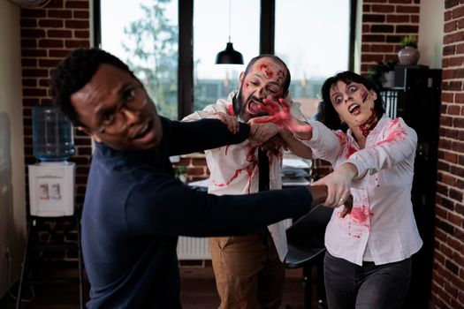Cruel spooky zombies chasing after businessman, frightened person running from brain eating bloodthirsty monsters. Scared man being afraid of undead aggressive corpses, walking dead.