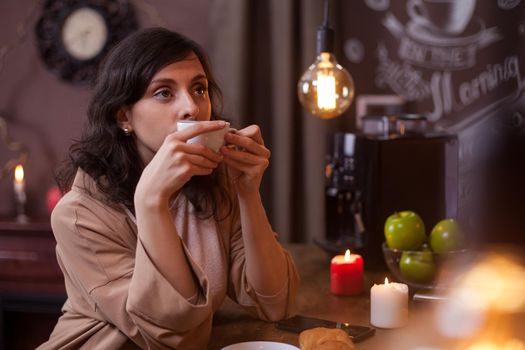 Portrait of a beautiful young woman holding a cup of coffee at the bar counter in a coffee shop. Beautiful woman relaxing in a coffee shop with a cup of coffee.