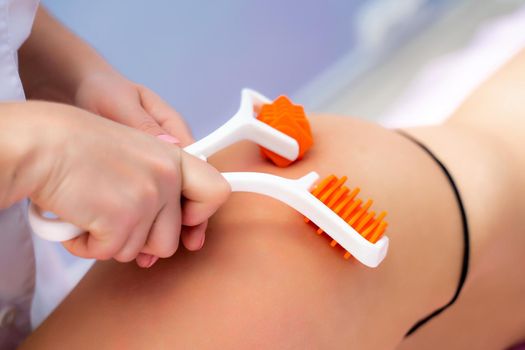 The masseur makes anti-cellulite massage using a roller massager. Physiotherapy and rehabilitation treatment
