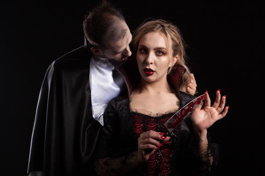 Portrait of a beautiful couple in medieval costumes with vampire style make-up for halloween. Charming vampire woman.