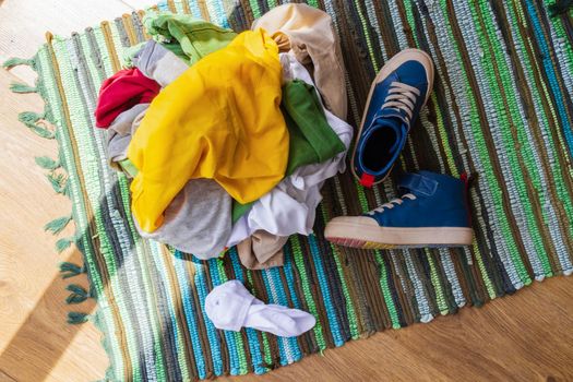 close-up, top view. A pile of colored dirty things, socks, sneakers piled on the floor in the morning sunlight. Real life concept, mess, lifestyle. Teenage room, transitional age