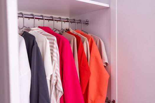 The basic wardrobe of a fashion stylist. Neutral colors: white, black, beige and accent French red. White wardrobe, gray hangers. Minimalism style