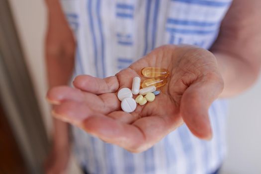 Close-up, there are many different pills and vitamins in the palm of an elderly woman. The concept of prevention, treatment of diseases in the elderly, support for old people, lifestyle.