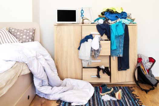 mess in the teenager's room, clothes scattered on the chest of drawers, on the floor, dirty shoes. There is an unmade white blanket on the bed. The concept of transitional age and education