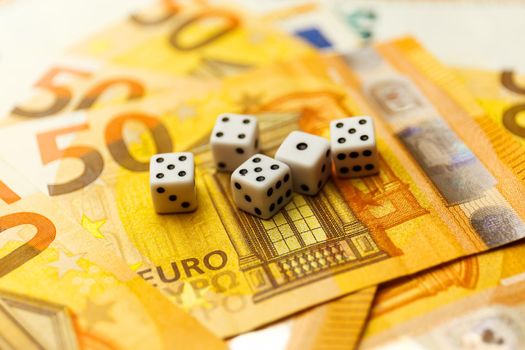 White Gaming dice and money on dark table. Money gambling concept, euro currency rate