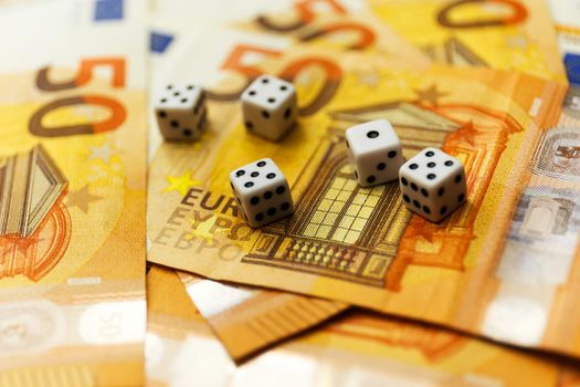 White Gaming dice and money on dark table. Money gambling concept, euro currency rate