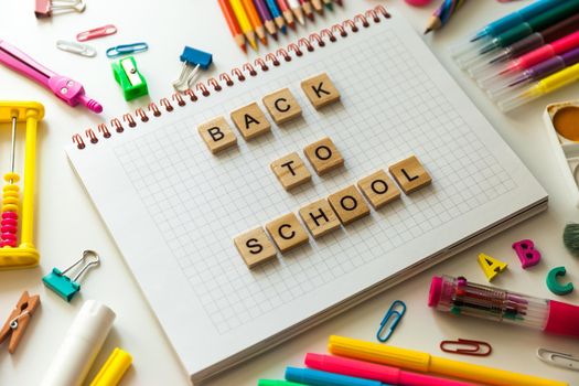 School office supplies and opened notebook on a desk with Back to school text made with wooden blocks
